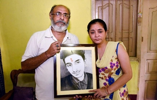 मृतक आदित्य की तस्वीर के साथ उसके माता पिता.