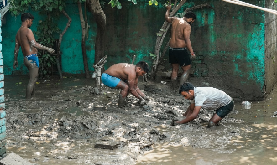 People clean an area filled with mud after the water level of the Yamuna river recedes in New Delhi, Sunday, Sept. 7, 2025. (PTI Photo/Shahbaz Khan)