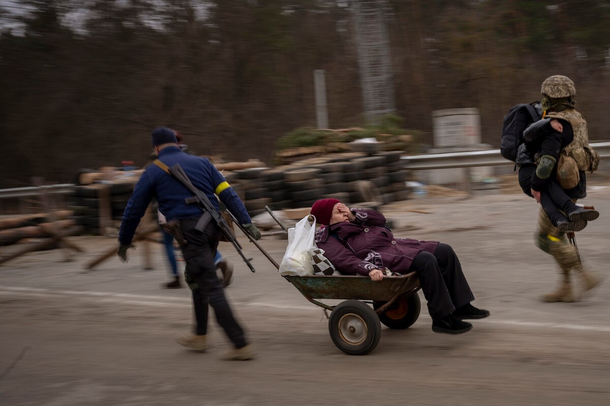 A Ukrainian soldier and a militia man help a fleeing family to cross the Irpin River on the outskirts of Kyiv, Ukraine.