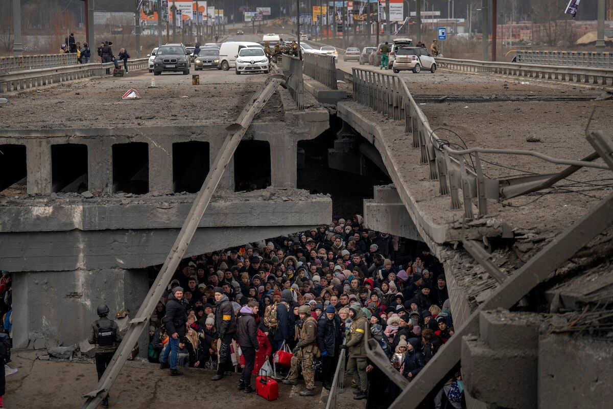 Ukrainians crowd under a destroyed bridge as they try to flee by crossing the Irpin River on the outskirts of Kyiv, Ukraine.