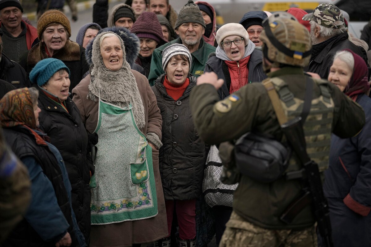 Civilians cheer along with a Ukrainian serviceman as a convoy of military and aid vehicles arrive at the formerly Russian-occupied Kyiv suburb of Bucha, Ukraine.
