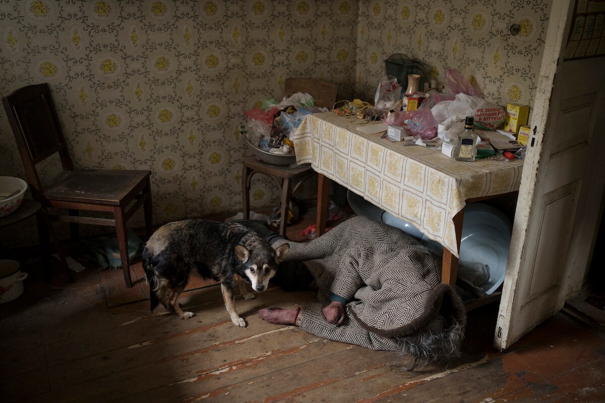 A dog stands next to the body of an elderly woman killed inside a home in Bucha on the outskirts of Kyiv, Ukraine.