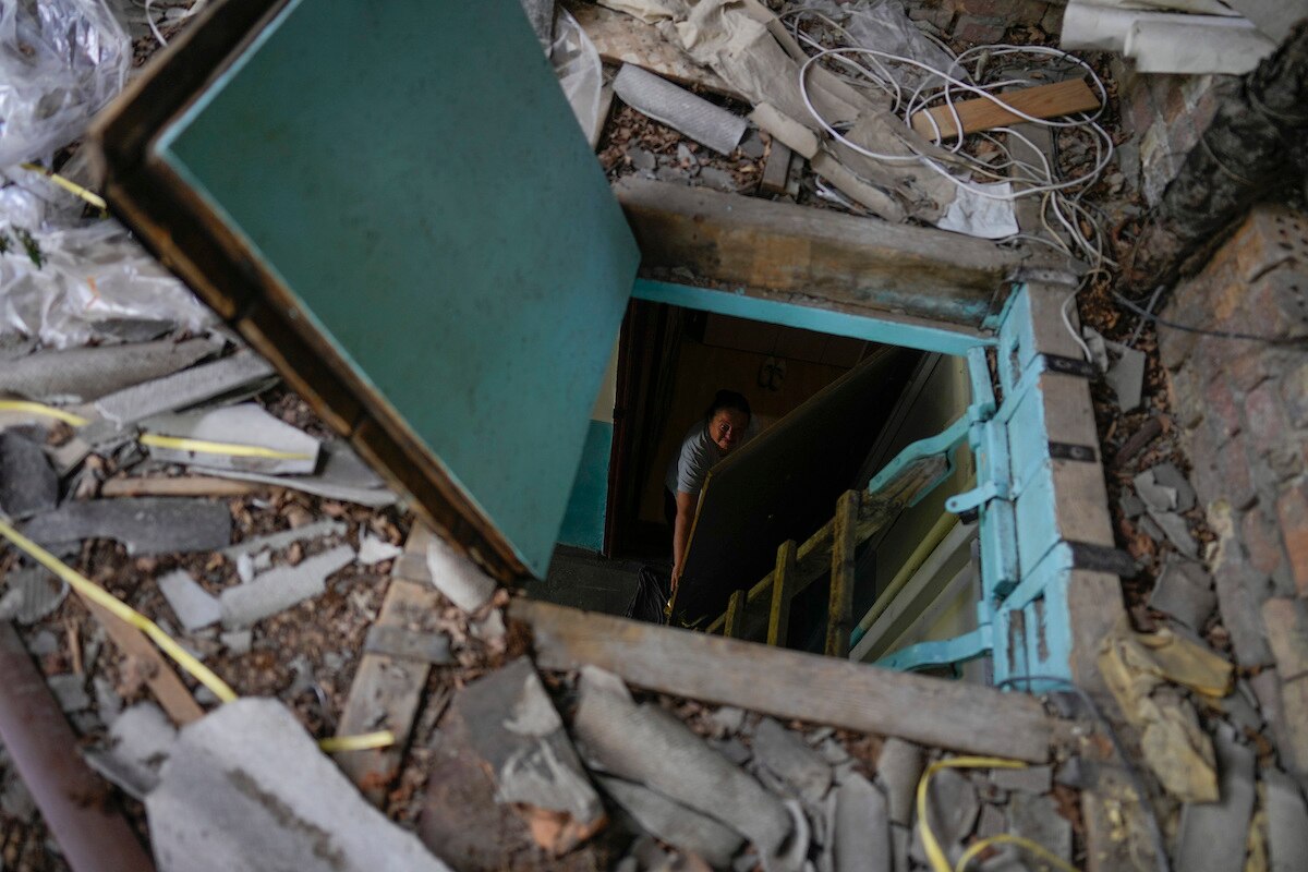 Liudmyla Voronina opens the skylight window of her roof as she stands inside her home that was damaged by attacks in Irpin on the outskirts of Kyiv, Ukraine.
