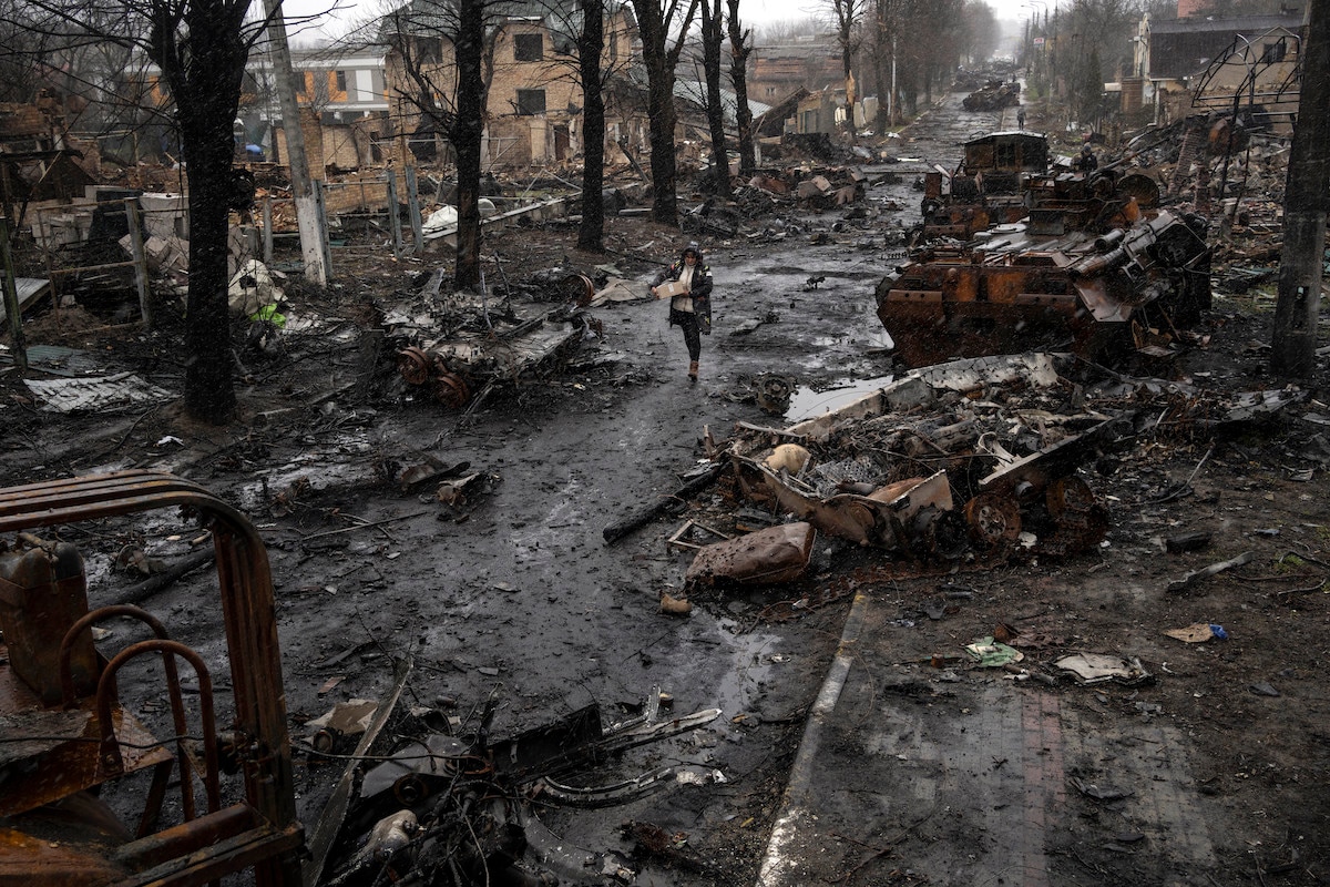 A woman navigates a debris-filled street where destroyed Russian military vehicles stand in Bucha on the outskirts of Kyiv, Ukraine.