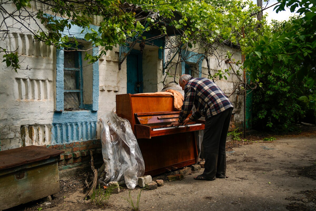 Anatolii Virko plays a piano outside a house likely damaged after a Russian bombing in Velyka Kostromka village, Ukraine.