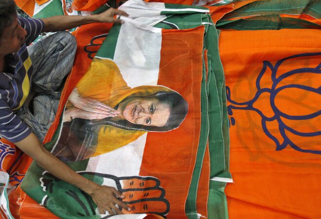 A worker looks at a Congress party flag carrying a picture of its party chief Sonia Gandhi next to flags of leading opposition Bharatiya Janata Party (BJP) inside an election campaigning material workshop. PHOTO: Reuters
