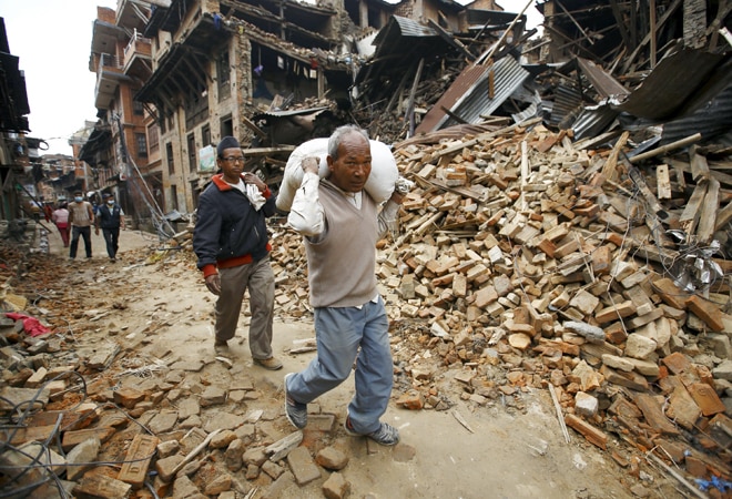 A man carrying goods walks along a street with houses that were collapsed by an earthquake at Bhaktapur, Nepal, on April 30, 2015. (Photo: Reuters)
