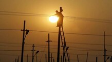 Govt to sell five per cent stake in Power Finance tomorrow A worker is silhouetted against the setting sun while installing an overhead electric cable pole on the banks of river Ganges in Allahabad December 26, 2014. (Photo: Reuters)