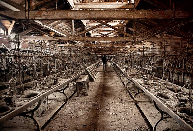 A caretaker is seen walking between two lines of more than a century-old decrepit machines inside one of the three fi latures of a silk factory A caretaker is seen walking between two lines of more than a century-old decrepit machines inside one of the three fi latures of a silk factory