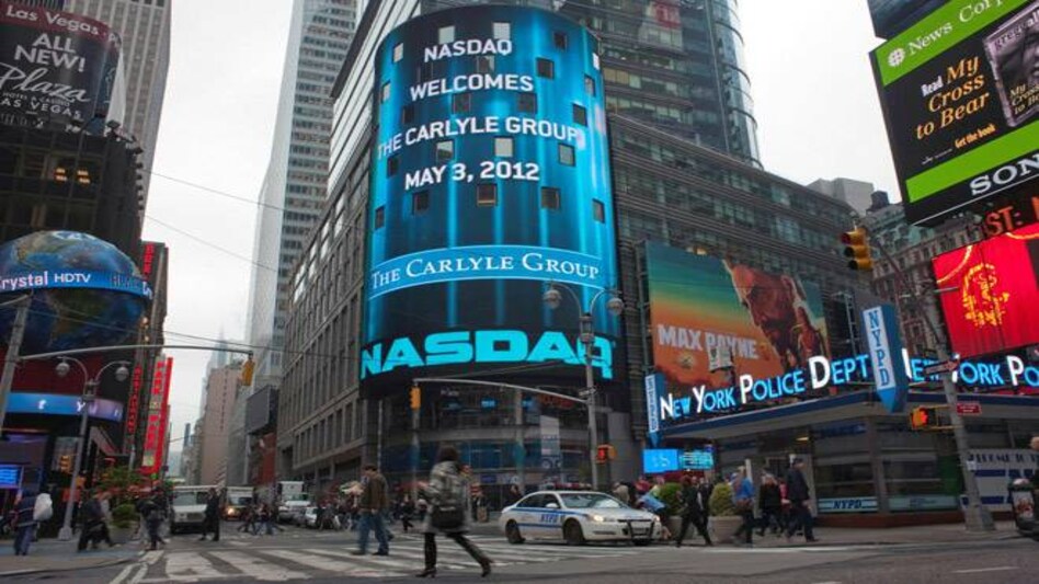 Passersby walk in front of the NASDAQ market site in New York's Times Square. Passersby walk in front of the NASDAQ market site in New York's Times Square.