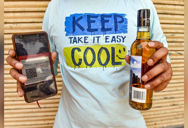 A person shows e-token near a liquor shop in Delhi (Photo credit: PTI) A person shows e-token near a liquor shop in Delhi (Photo credit: PTI)