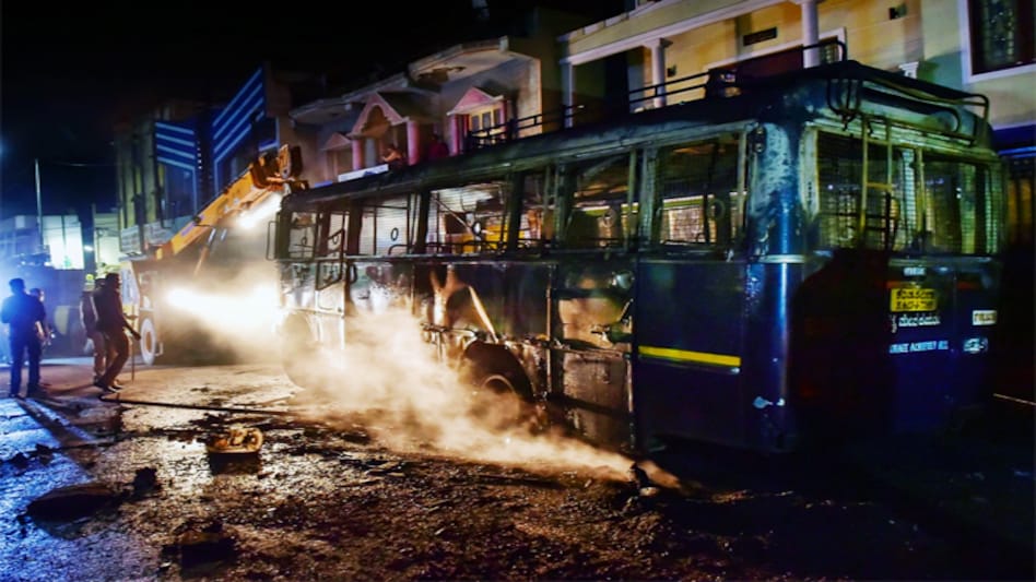 Charred remains of a vehicle vandalised by a mob over a social media post by a relative of a MLA, in Bengaluru. Charred remains of a vehicle vandalised by a mob over a social media post by a relative of a MLA, in Bengaluru.