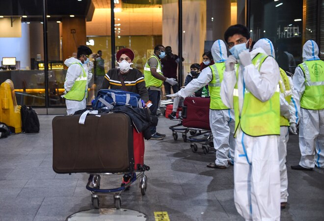 Municipal workers in personal protective equipment look on as passengers from United Kingdom arrive at the Chhatrapati Shivaji Maharaj International Airport, in Mumbai (Photo: PTI) Municipal workers in personal protective equipment look on as passengers from United Kingdom arrive at the Chhatrapati Shivaji Maharaj International Airport, in Mumbai (Photo: PTI)