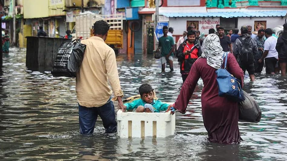 Commuters wade through a waterlogged area following heavy rain in Chennai. (PTI Photo) Commuters wade through a waterlogged area following heavy rain in Chennai. (PTI Photo)