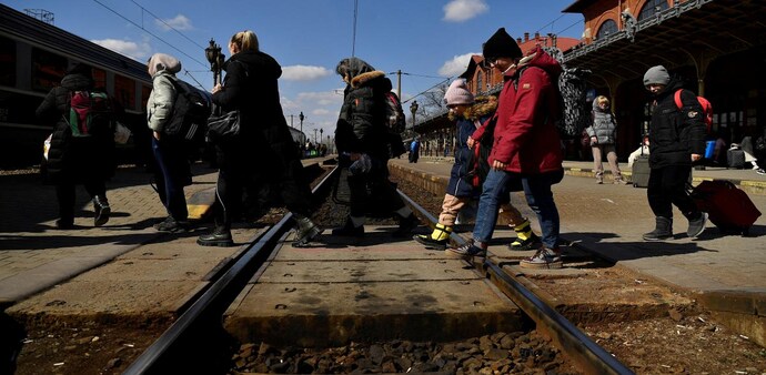 Refugees walk across train tracks to board a train to Bucharest at Suceava train station after fleeing Ukraine to the Siret border crossing in Romania. Refugees walk across train tracks to board a train to Bucharest at Suceava train station after fleeing Ukraine to the Siret border crossing in Romania.
