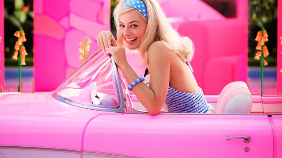 The studio also shared Robbie's first look which sees her in a pink convertible, wearing a blue dress and a polka dot headband behind the wheel. The studio also shared Robbie's first look which sees her in a pink convertible, wearing a blue dress and a polka dot headband behind the wheel.
