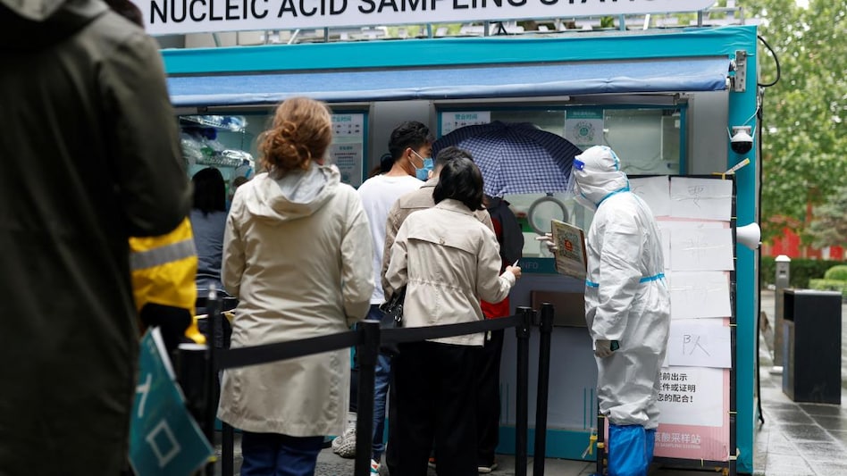 People line up to get tested next to a staff member wearing PPE at a mobile nucleic acid testing site outside a shopping mall in China. (Photo: Reuters) People line up to get tested next to a staff member wearing PPE at a mobile nucleic acid testing site outside a shopping mall in China. (Photo: Reuters)