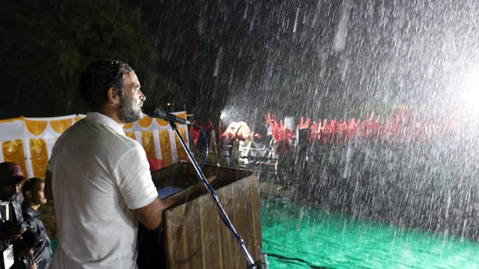 As the Wayanad MP chose to continue his speech, the crowds cheered for him, even as many were seen holding up chairs to ward off the torrential rain. As the Wayanad MP chose to continue his speech, the crowds cheered for him, even as many were seen holding up chairs to ward off the torrential rain.