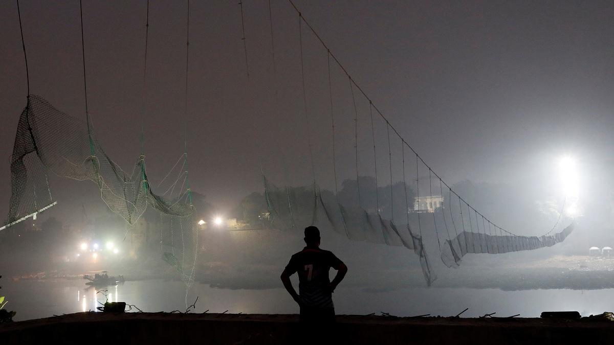 A security personnel stands near a damaged suspension bridge after it collapsed on Sunday, in Morbi town A security personnel stands near a damaged suspension bridge after it collapsed on Sunday, in Morbi town
