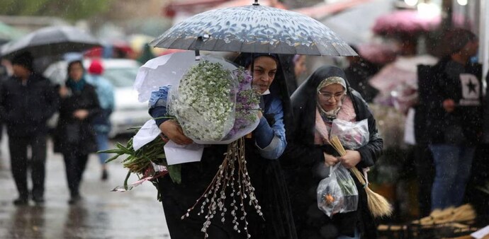 Iranian women walk through rain in a flower market, ahead of Nowruz, the Iranian New Year, in Tehran, Iran Iranian women walk through rain in a flower market, ahead of Nowruz, the Iranian New Year, in Tehran, Iran