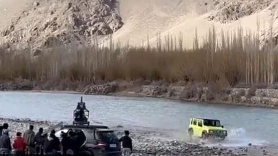 The 15-second video shows a Maruti Jimny SUV driving across a river stream, demonstrating its ability to handle challenging terrain while a TV crew shoots alongside. The 15-second video shows a Maruti Jimny SUV driving across a river stream, demonstrating its ability to handle challenging terrain while a TV crew shoots alongside.