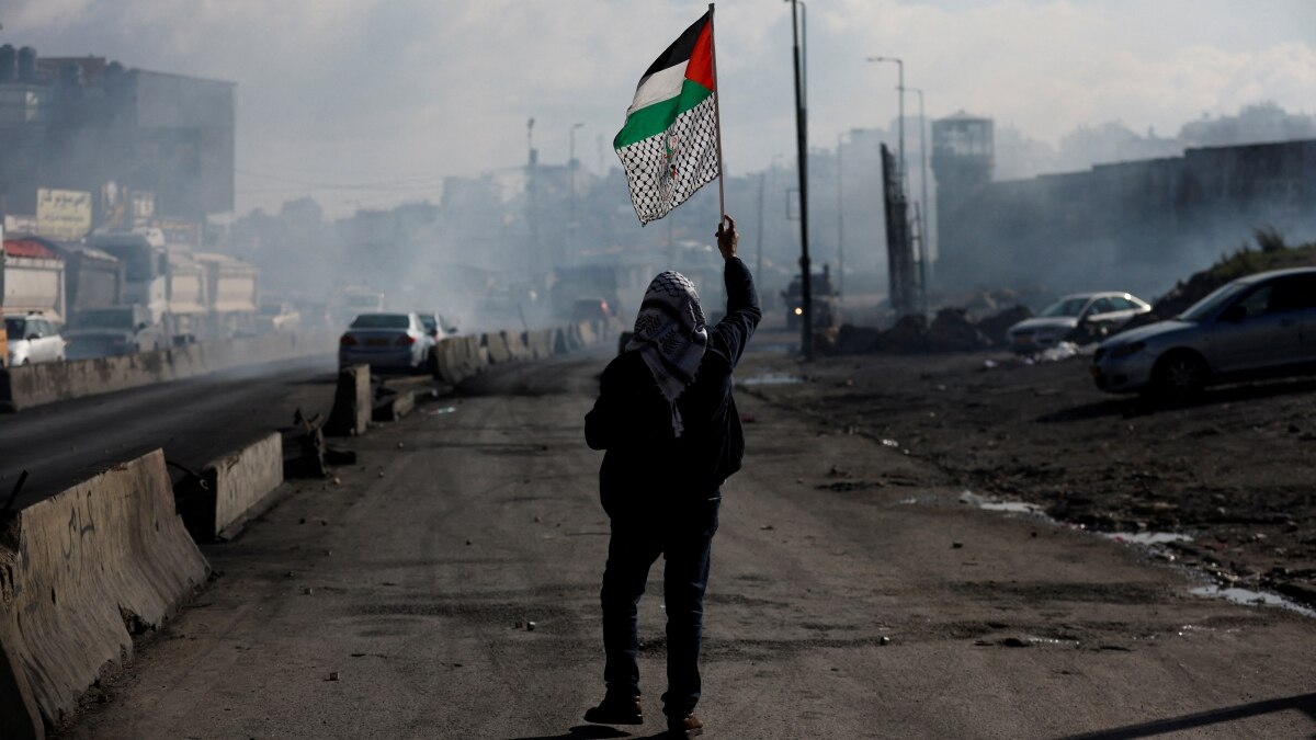 A man walks with a Palestinian flag near Qalandia in the Israeli-occupied West Bank A man walks with a Palestinian flag near Qalandia in the Israeli-occupied West Bank