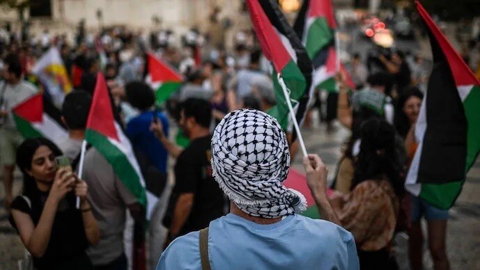 A protestor with a keffieh waves a Palestinian flag during a rally in support of Palestine.(Image: AFP) A protestor with a keffieh waves a Palestinian flag during a rally in support of Palestine.(Image: AFP)