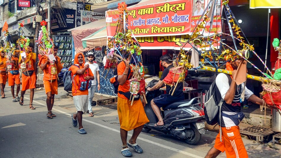 Kanwariyas walk past the shops on which banners with shopkeepers’ name were put up on Kanwar Marg after an order issued by Uttar Pradesh government in Muzaffarnagar on July 20. Kanwariyas walk past the shops on which banners with shopkeepers’ name were put up on Kanwar Marg after an order issued by Uttar Pradesh government in Muzaffarnagar on July 20.