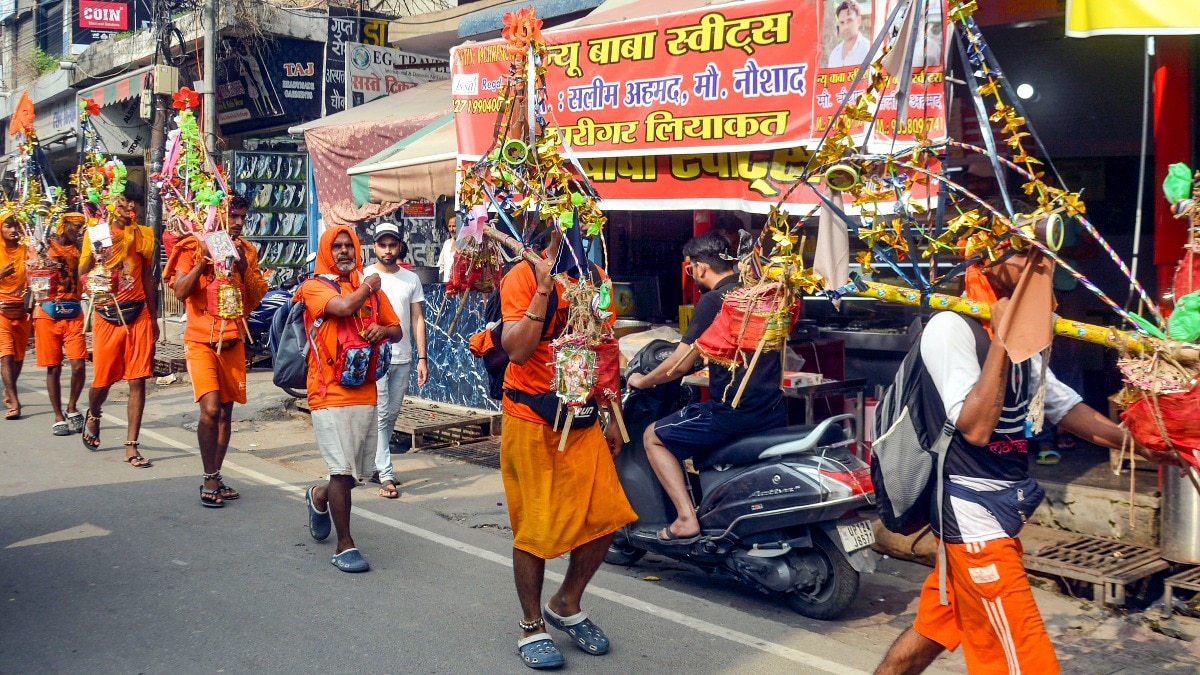Kanwariyas walk past the shops on which banners with shopkeepers' name were put up on Kanwar Marg after an order issued by Uttar Pradesh government in Muzaffarnagar. (Photo: PTI) Kanwariyas walk past the shops on which banners with shopkeepers' name were put up on Kanwar Marg after an order issued by Uttar Pradesh government in Muzaffarnagar. (Photo: PTI)
