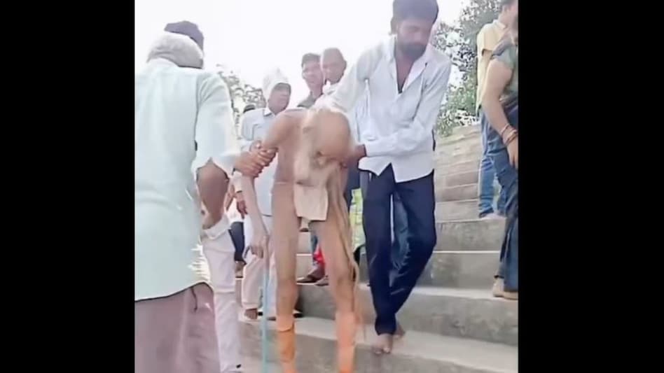 The 24-second video shows two men helping an elderly man with a white beard who is hunched over and using a walking stick. The 24-second video shows two men helping an elderly man with a white beard who is hunched over and using a walking stick.