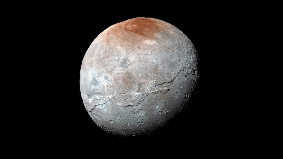 Charon’s surface is mostly grey with reddish-brown regions around its poles composed of organic materials. Charon’s surface is mostly grey with reddish-brown regions around its poles composed of organic materials.