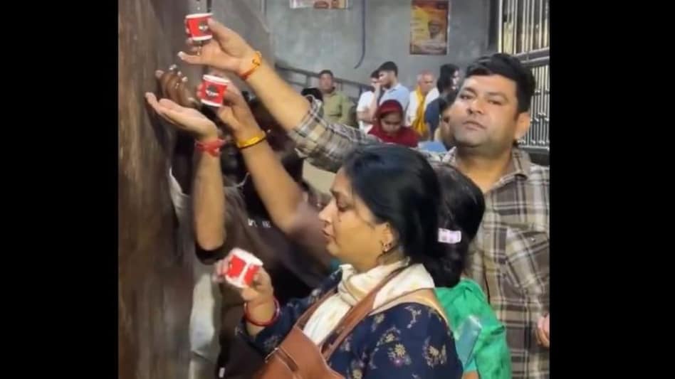 In the clip shared on X, people are seen using paper cups to collect the water coming from a stone statue. In the clip shared on X, people are seen using paper cups to collect the water coming from a stone statue.