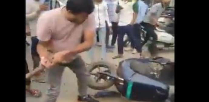 In the video, a man wearing a white T-shirt and blue jeans is seen angrily smashing a scooter with a hammer outside an Ola showroom. In the video, a man wearing a white T-shirt and blue jeans is seen angrily smashing a scooter with a hammer outside an Ola showroom.