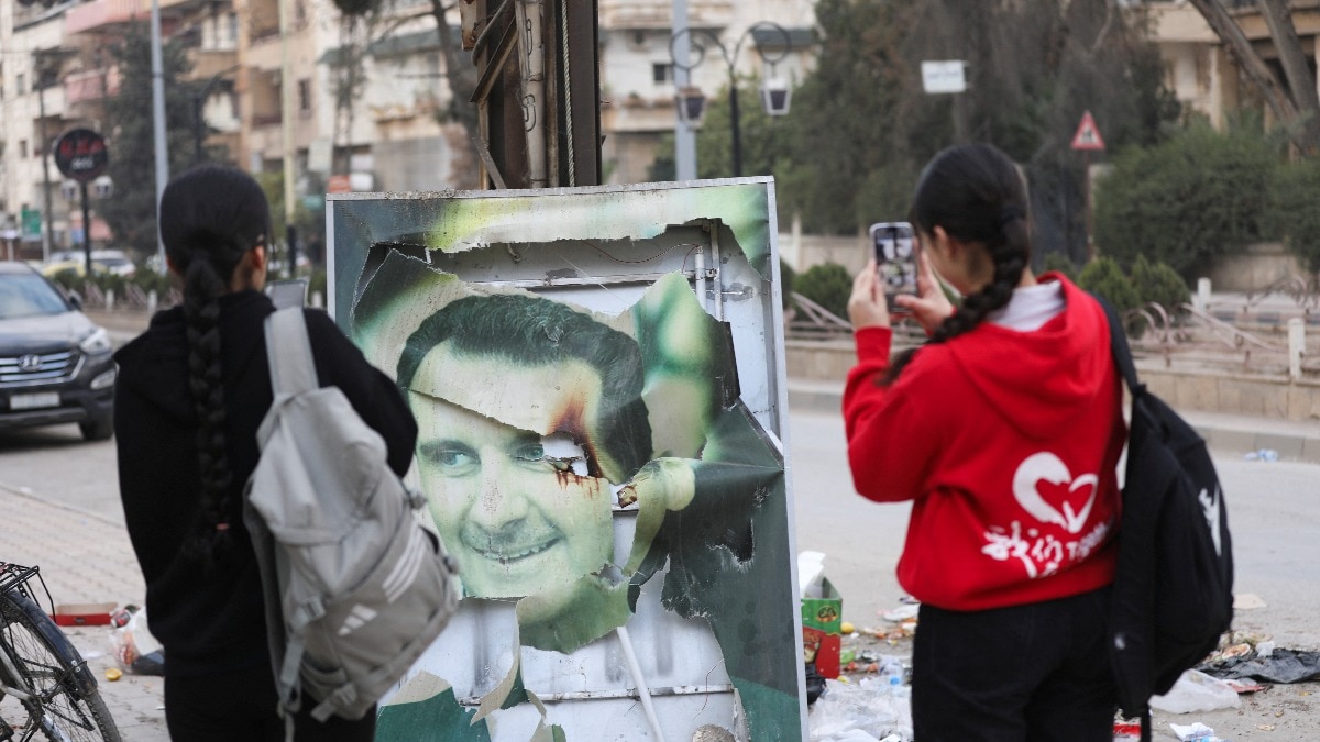 Women use their phones near a damaged picture of Syrian President Bashar al-Assad as people celebrate after Syrian rebels announced that they have ousted Assad on December 8. (Reuters) Women use their phones near a damaged picture of Syrian President Bashar al-Assad as people celebrate after Syrian rebels announced that they have ousted Assad on December 8. (Reuters)