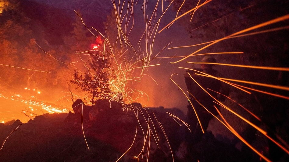The wind whips embers while a firefighter battles the fire in the Angeles National Forest near Mt. Wilson as the wildfires burn in the Los Angeles area, during the Eaton Fire in Altadena, California. The wind whips embers while a firefighter battles the fire in the Angeles National Forest near Mt. Wilson as the wildfires burn in the Los Angeles area, during the Eaton Fire in Altadena, California.