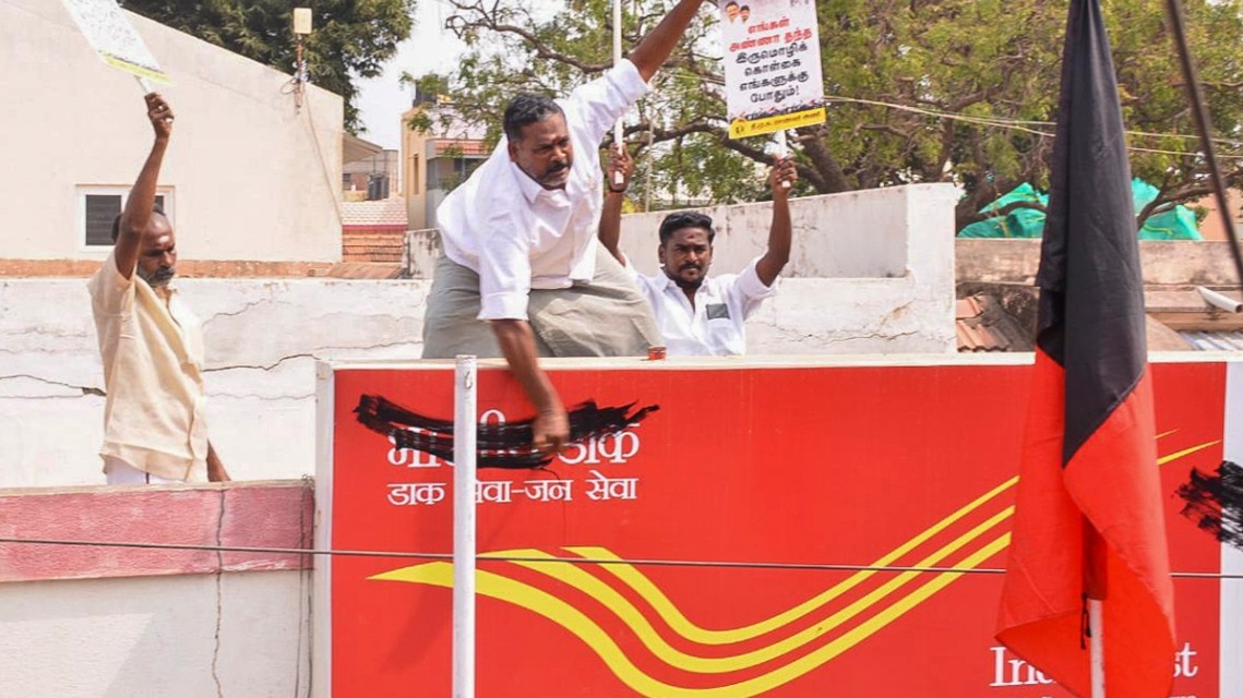 DMK workers paint over the Hindi name board of a post office during a protest against the Centre's three-language policy in Madurai DMK workers paint over the Hindi name board of a post office during a protest against the Centre's three-language policy in Madurai