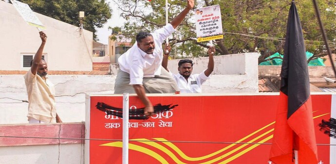 DMK workers paint over the Hindi name board of a post office during a protest against the Centre's three-language policy in Madurai DMK workers paint over the Hindi name board of a post office during a protest against the Centre's three-language policy in Madurai