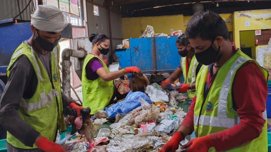 Waste workers working in safety gear at a waste sorting belt Waste workers working in safety gear at a waste sorting belt