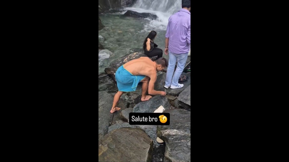 The foreign man is seen collecting wrappers and other plastic waste from the ground while locals watch him go about his act. 