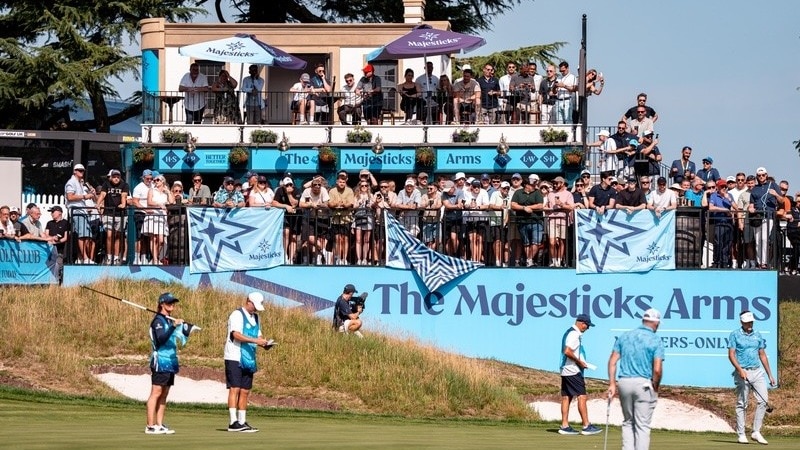 Majesricks co-captains Lee Westwood and Ian Poulter study their putting lines on the ninth green as fans watch from the Majesticks Arms pub during the first round of LIV Golf UK by JCB in Rocester. Image courtesy LIV Golf.