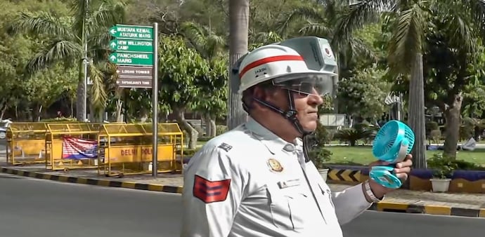 A traffic police personnel uses an electric hand fan and AC helmet on a summer day in New Delhi (PTI Photo) A traffic police personnel uses an electric hand fan and AC helmet on a summer day in New Delhi (PTI Photo)