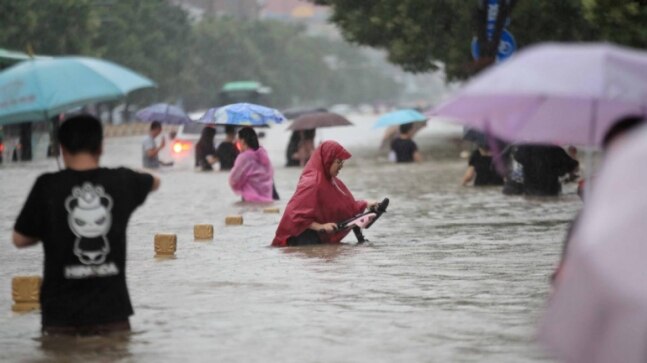 Commuters stuck in waist-deep water due to heavy flooding in central China | See Pics