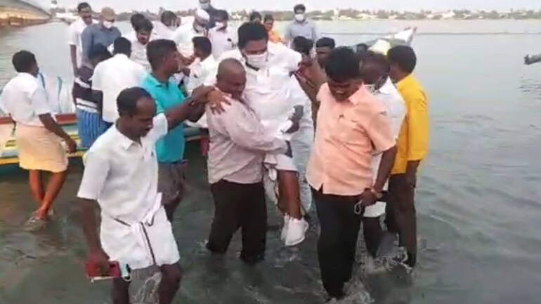 Fishermen carry the Tamil Nadu Minister of Fisheries from the boat to shore | Clock