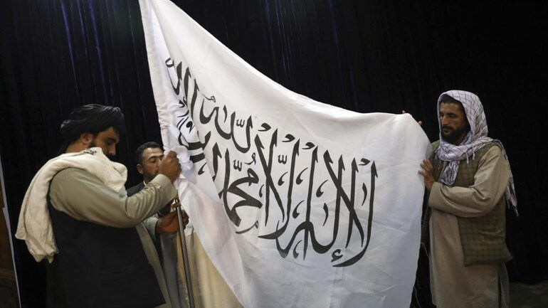 Taliban fighters hoist their flag ahead of the press conference in Kabul on Tuesday