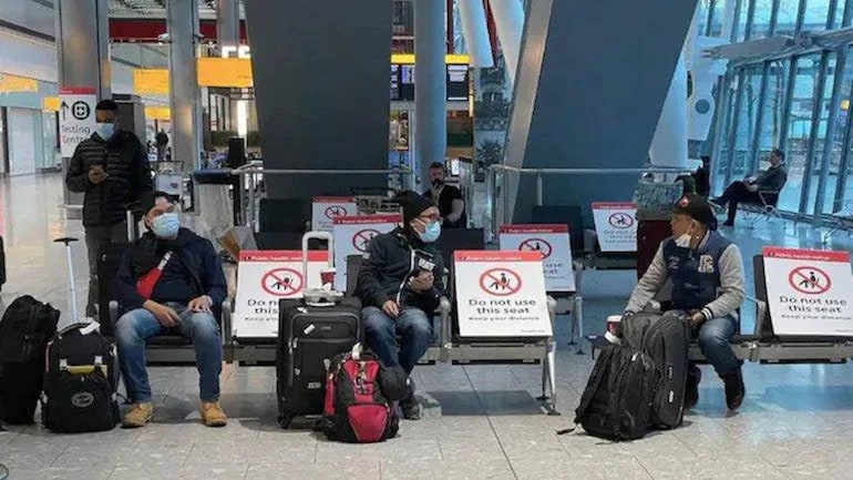 Passengers sitting in waiting area of London's Heathrow Airport
