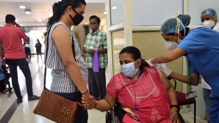 A woman being administered Covid-19 vaccine by a healthcare worker