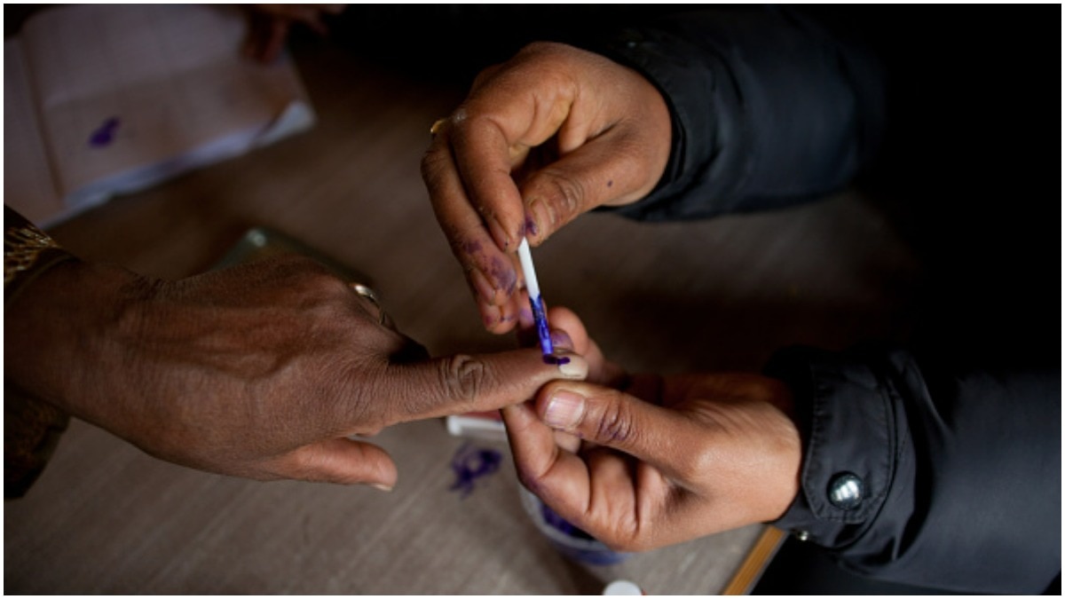 A poll booth worker inks the index finger of a voter