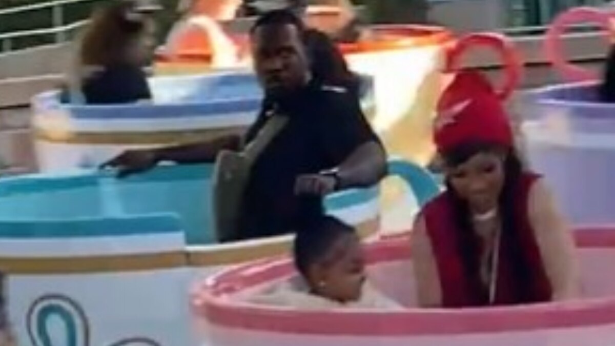 Cardi B takes a ride in Disneyland with daughter Kulture and their bodyguard. His expression is