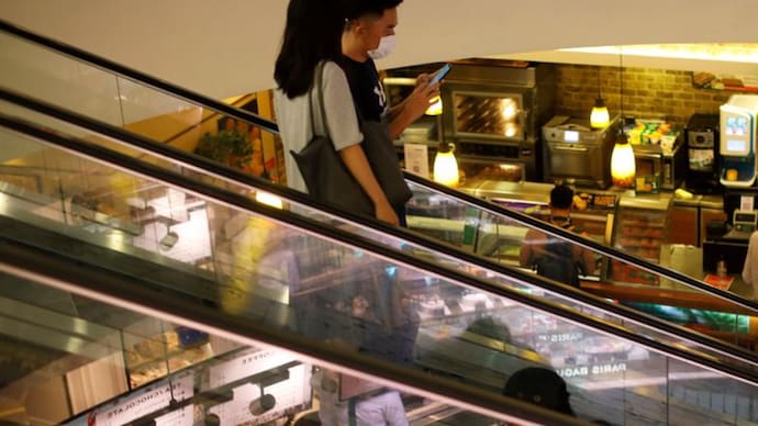 Las personas que usan máscaras faciales protectoras suben por una escalera mecánica en un centro comercial. (Foto de Reuters/representante) Personas con máscaras protectoras.
