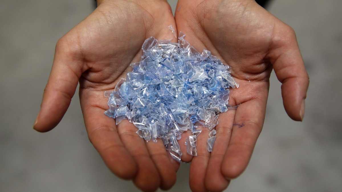 A worker handles ground plastic flakes ready to be recycled in Switzerland. Photographer: Stefan Wermuth/Bloomberg